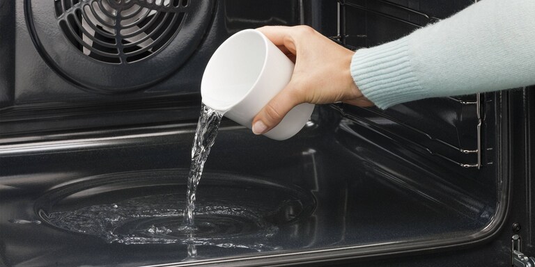 Someone pouring water into the oven cavity